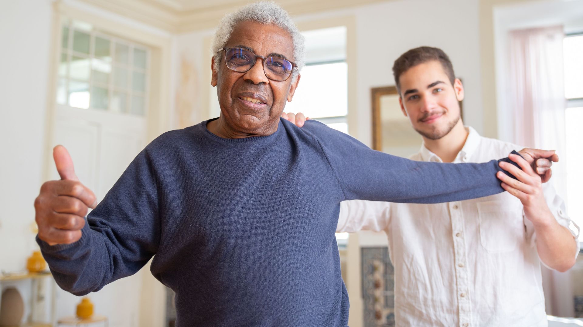 Elderly man smiling with caregiver in a supportive home environment, promoting health and happiness.