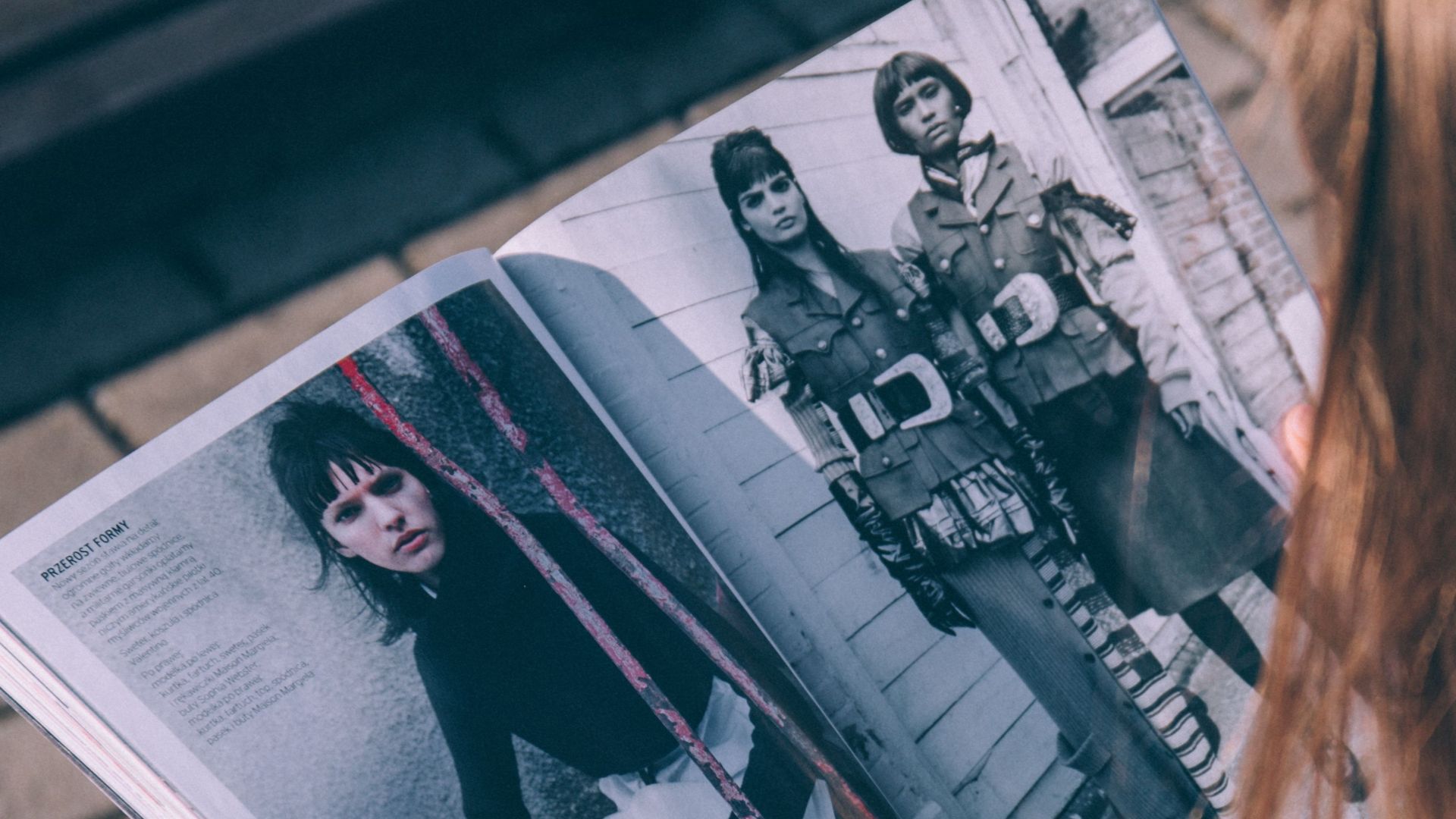 Outdoor shot of a woman reading a fashion magazine with a focus on style and fashion details.