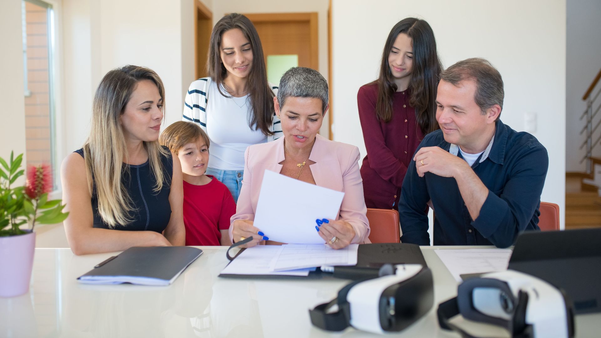 A family meeting with a female realtor reviewing documents in a bright, modern room.