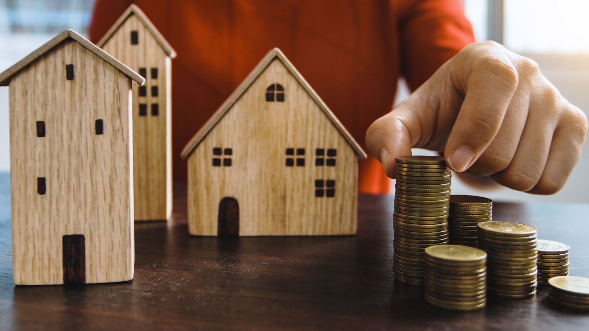 Planning investments with stacked coins and model houses on a table.