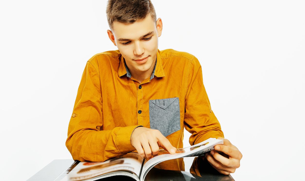 A young man reads a book. The guy is browsing the magazine. Reading with emotions. Teaching.