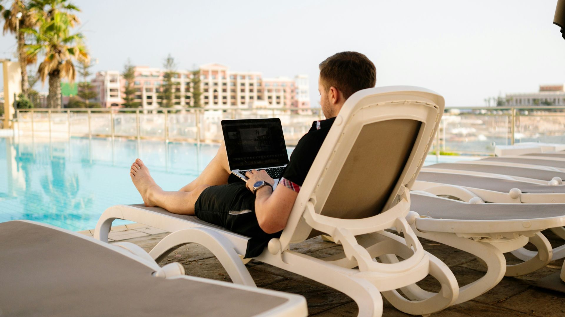 man on sun lounger using laptop