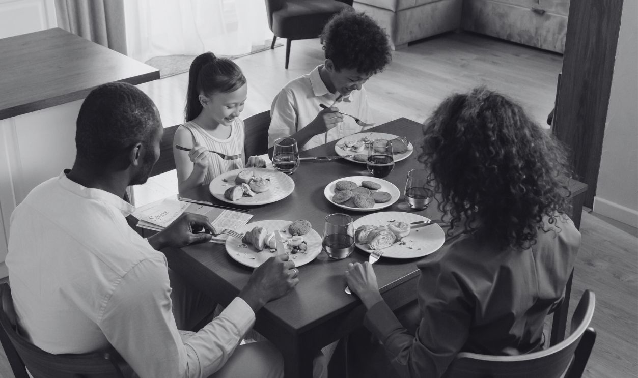 A family of four gathered around a table enjoying a breakfast meal 