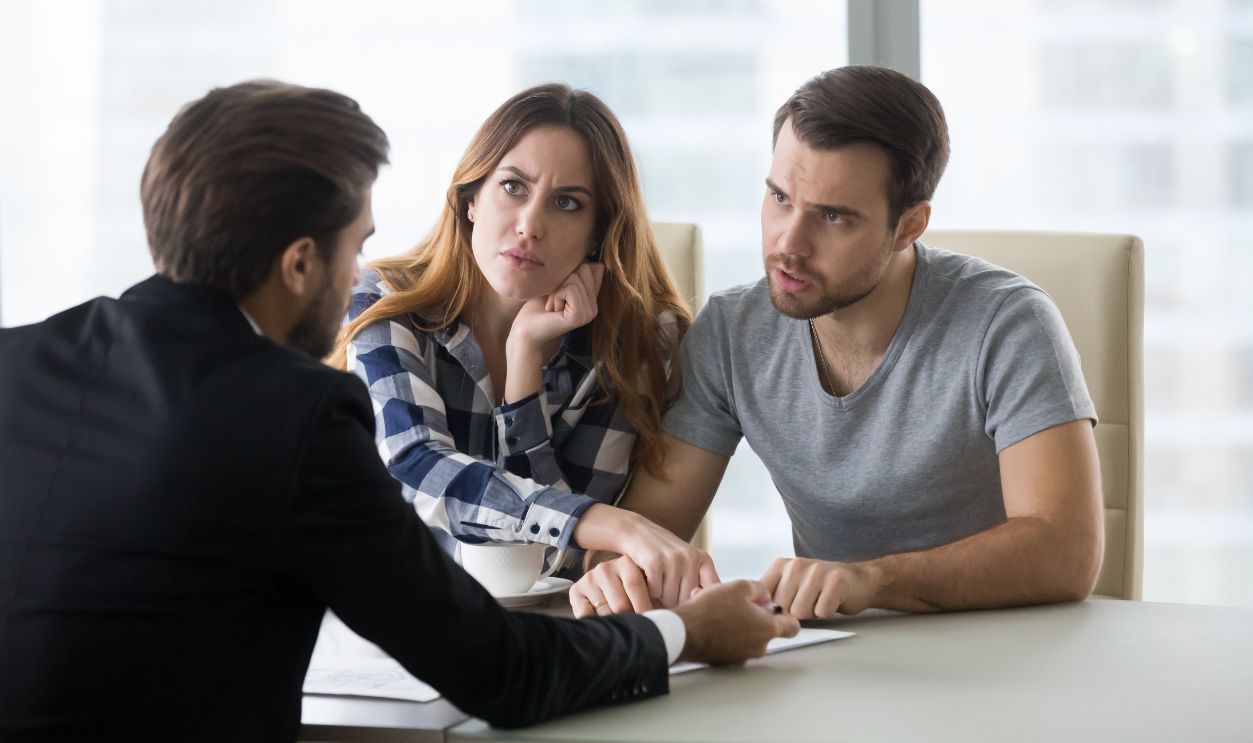 Angry dissatisfied couple arguing meeting lawyer or manager having legal fight complaints on bad client service, annoyed mad customers claiming change in contract terms demanding fraud compensation