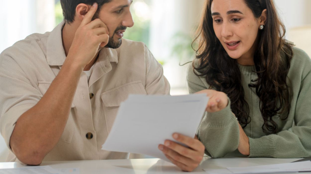 Shutterstock-2626993875, Finance and family paperwork. Hispanic Latin Couple checking bank account, financial statements and reports, doing online banking on laptop with documents at home