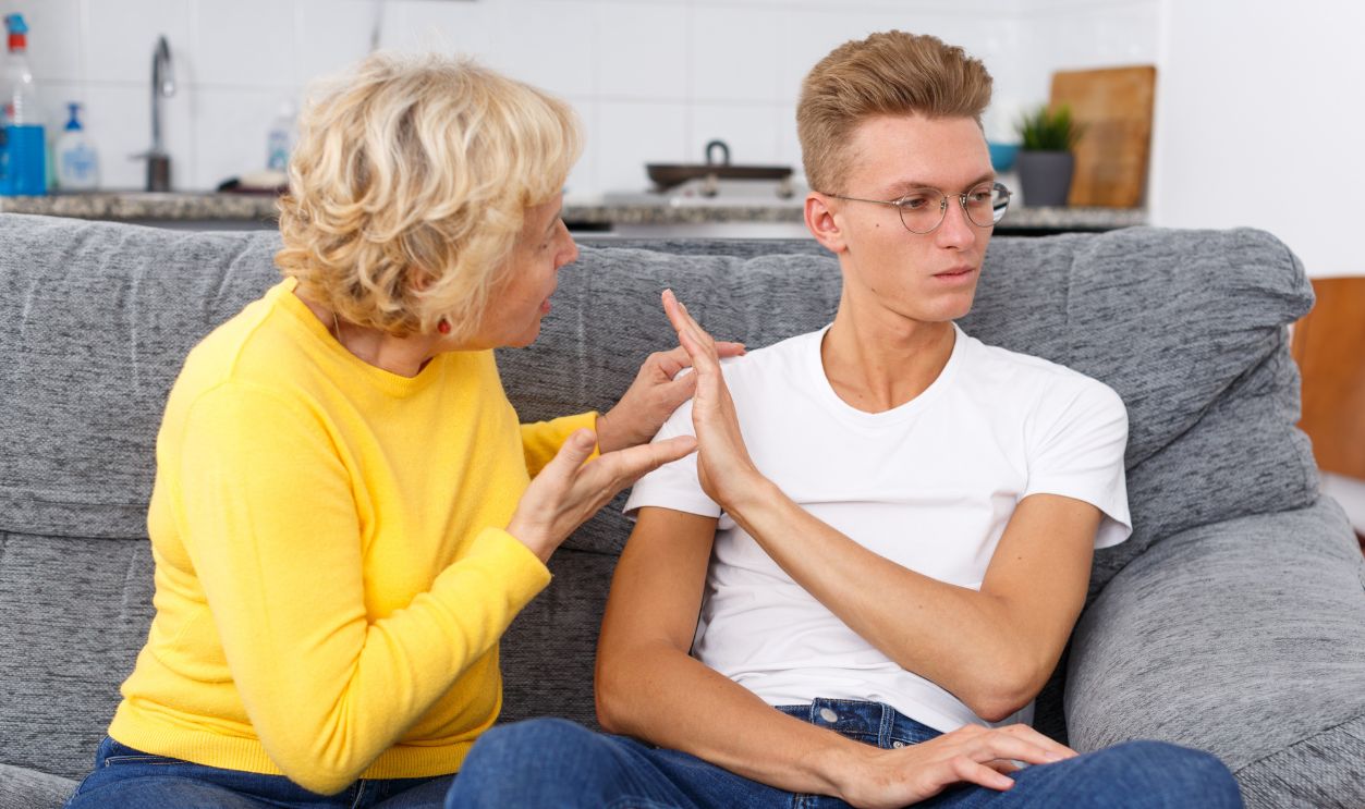 Mature woman scolding her upset adult son in kitchen