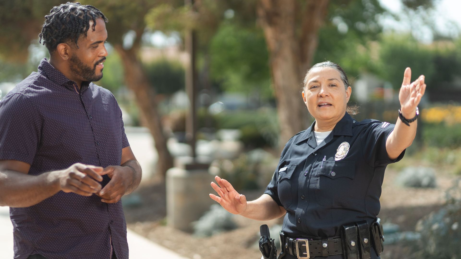 Police officer in uniform engaging in a conversation with a man on a sunny day, promoting community relations.