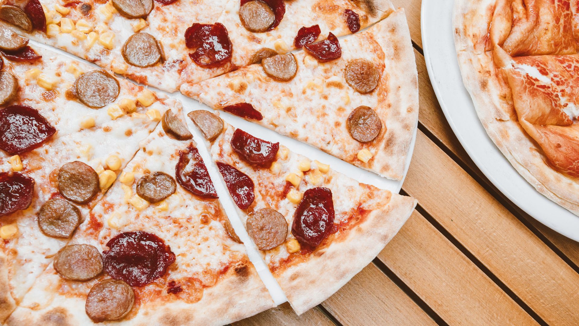 Delicious pepperoni and sausage pizza slices on a rustic wooden table.