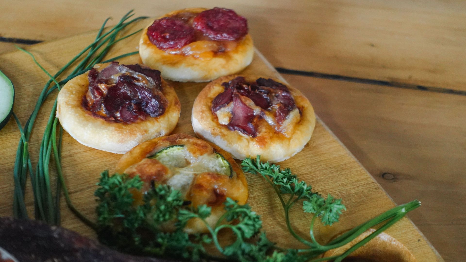 Delicious mini pizzas topped with beef biltong and herbs on a wooden board in Bujumbura, Burundi.