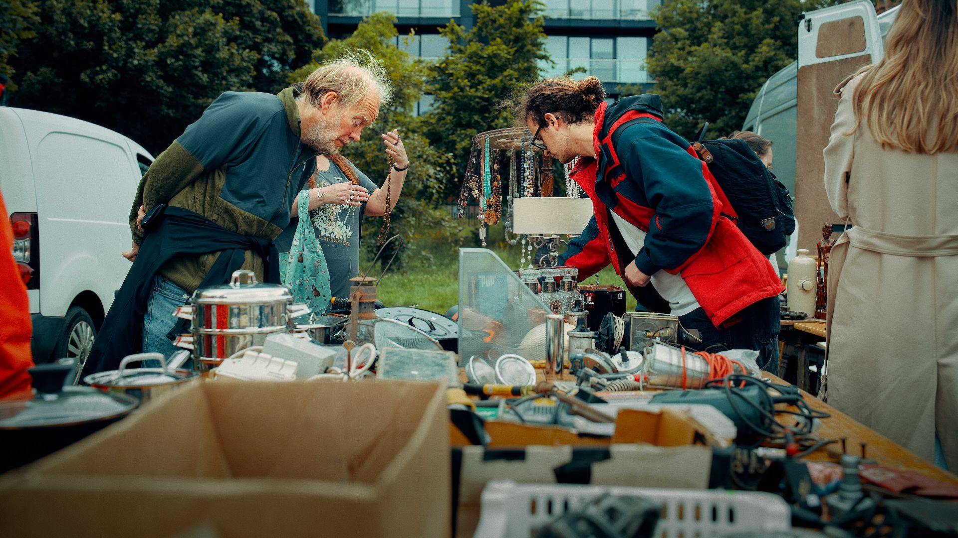 Two people examine goods at an outdoor market stall