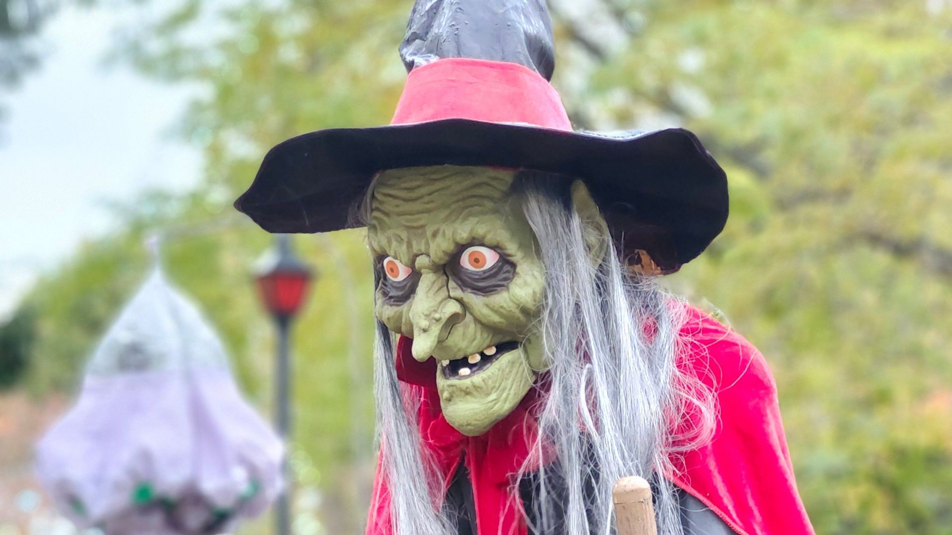 Spooky witch decoration with pointy hat and cape in an outdoor setting, perfect for Halloween.