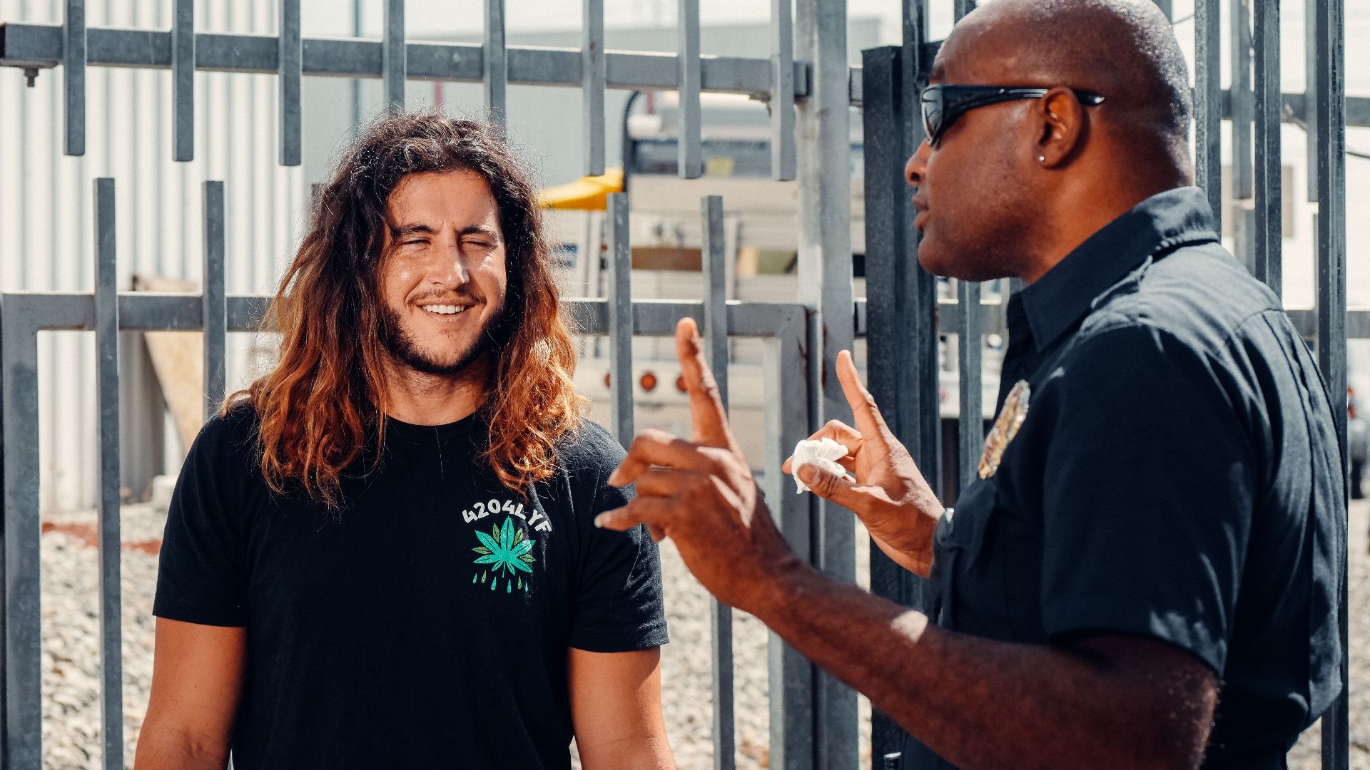 A police officer engages in conversation with a civilian outside on a sunny day.