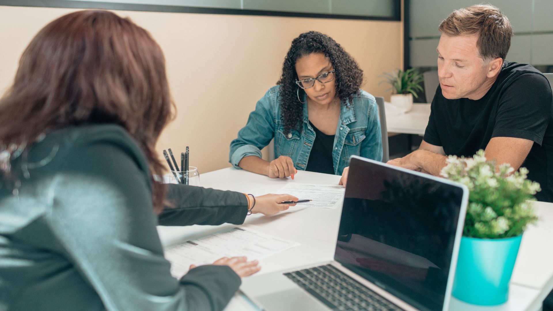 Couple meeting with advisor for adoption process in a modern office setting.