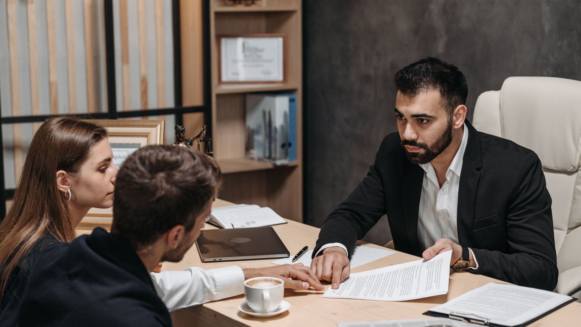 Lawyer discussing legal documents with clients at office desk.