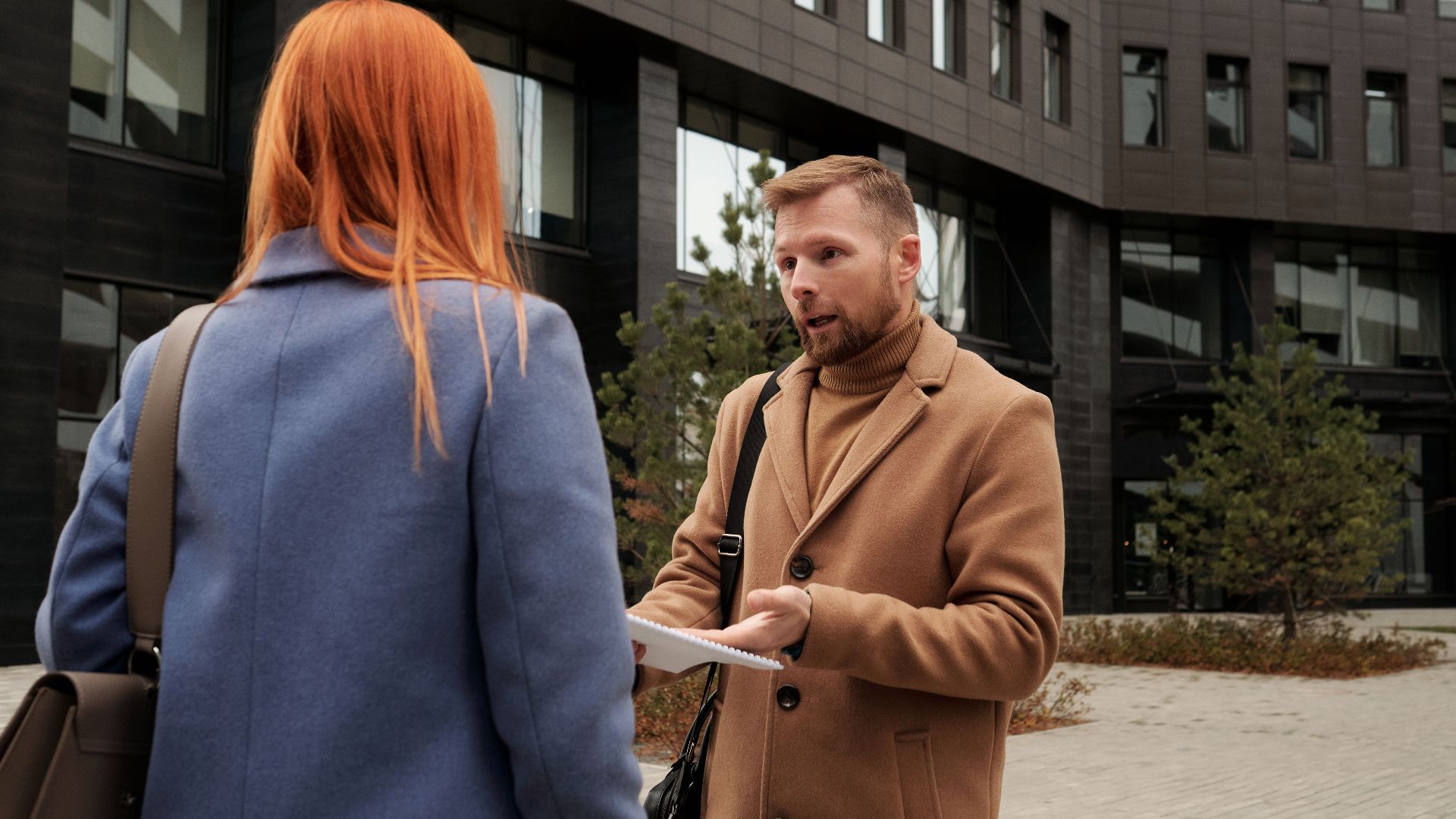 Two business professionals in conversation outside an urban office building.