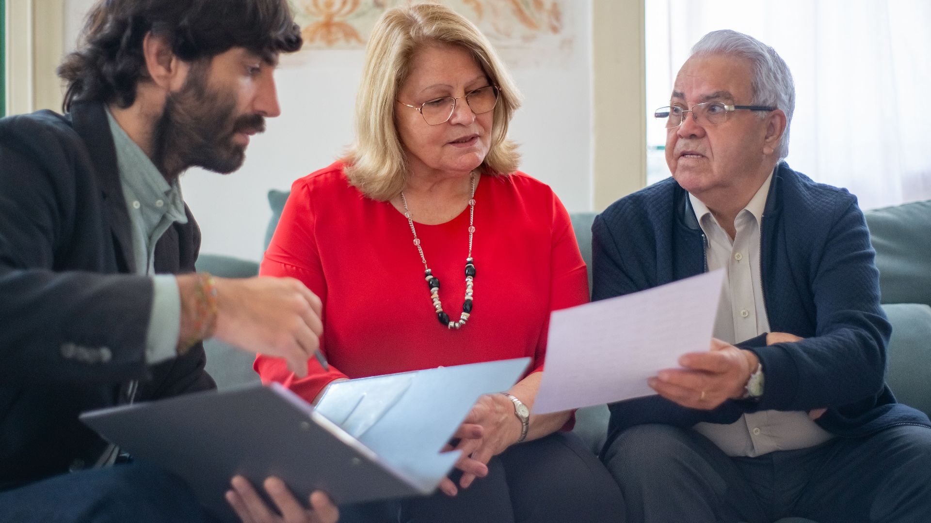 Senior couple consulting with a professional advisor, discussing documents indoors.