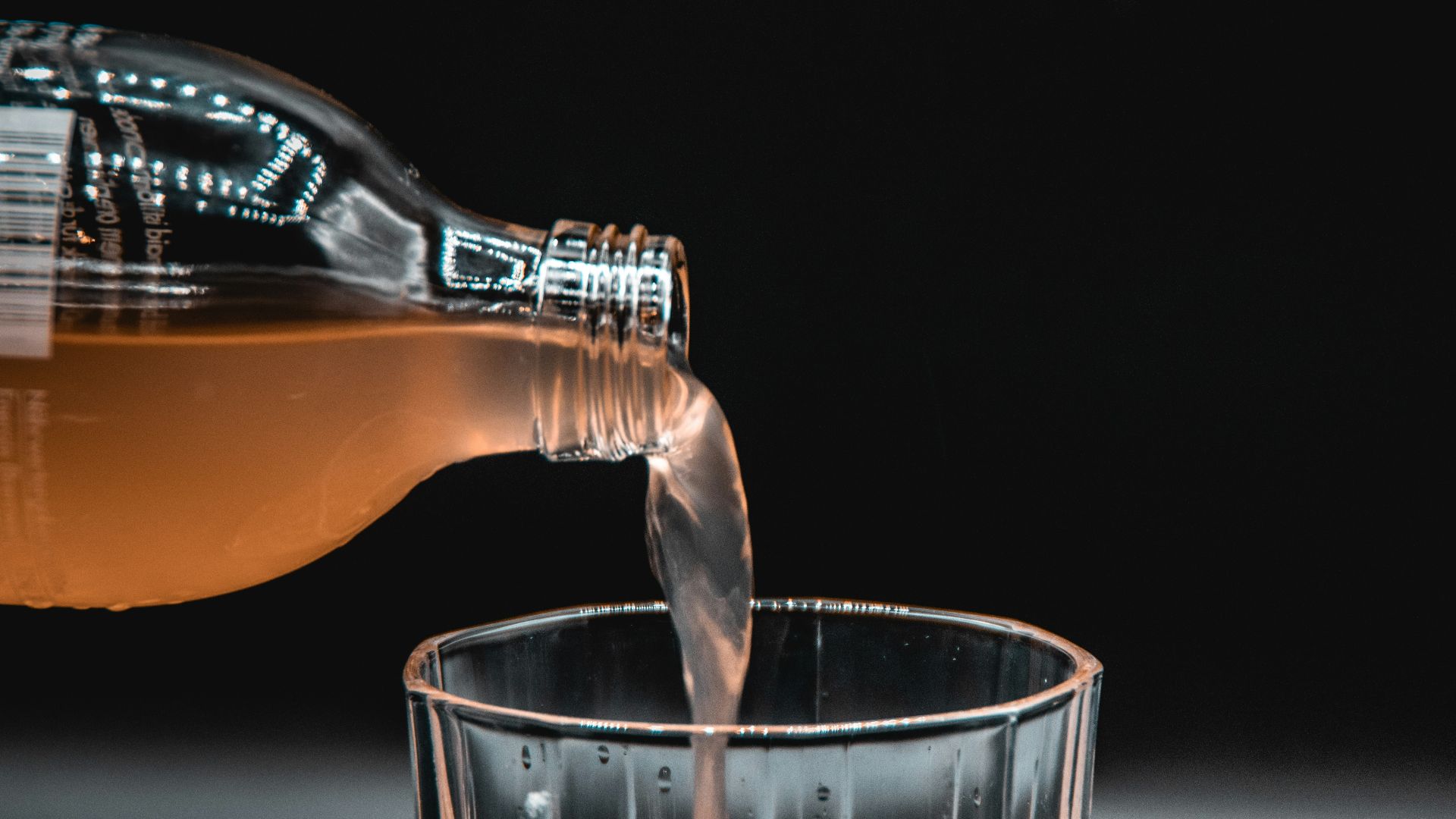 person pouring water on clear drinking glass