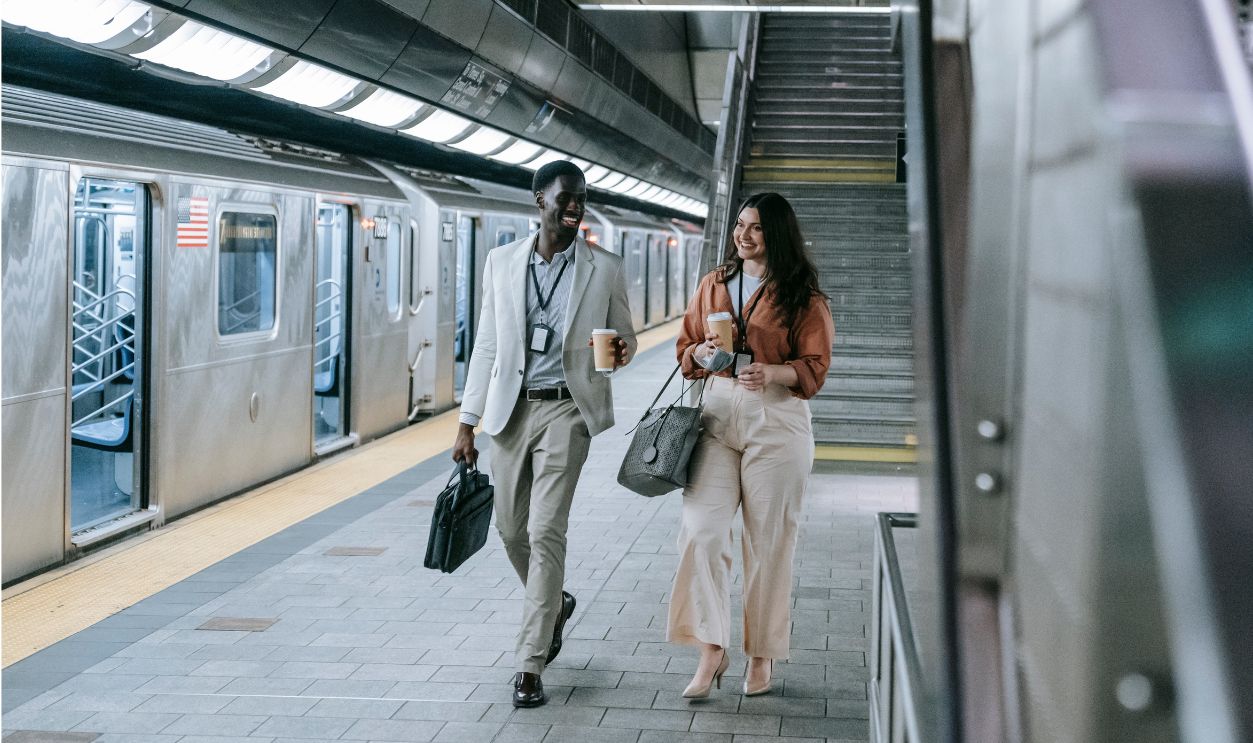 Two smiling professionals walking together in a subway station, capturing the essence of daily commuting.