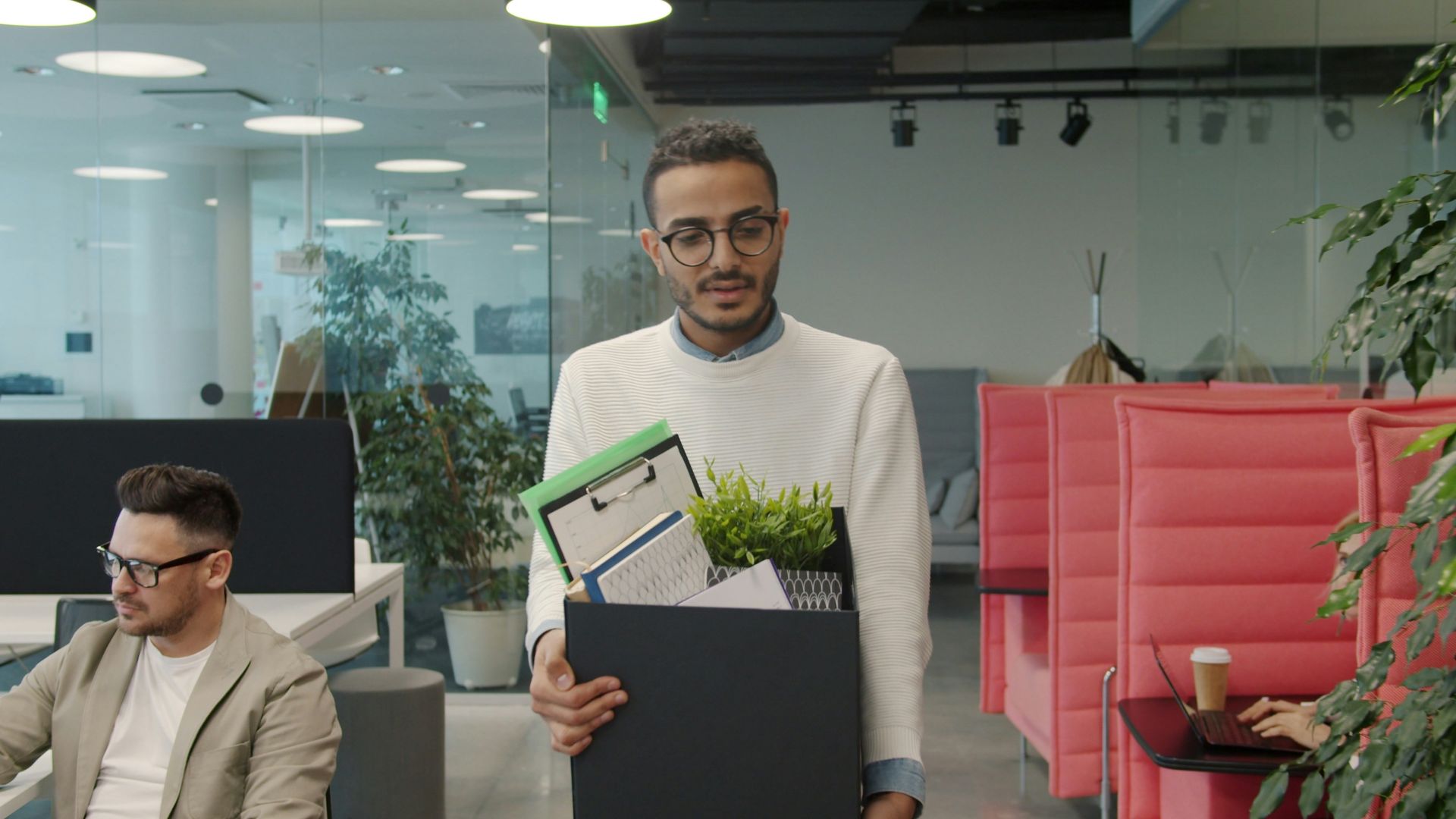 Man carrying box of belongings in modern office