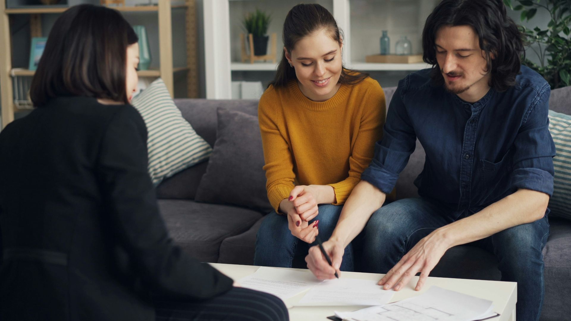 three people sitting on a couch looking at a piece of paper