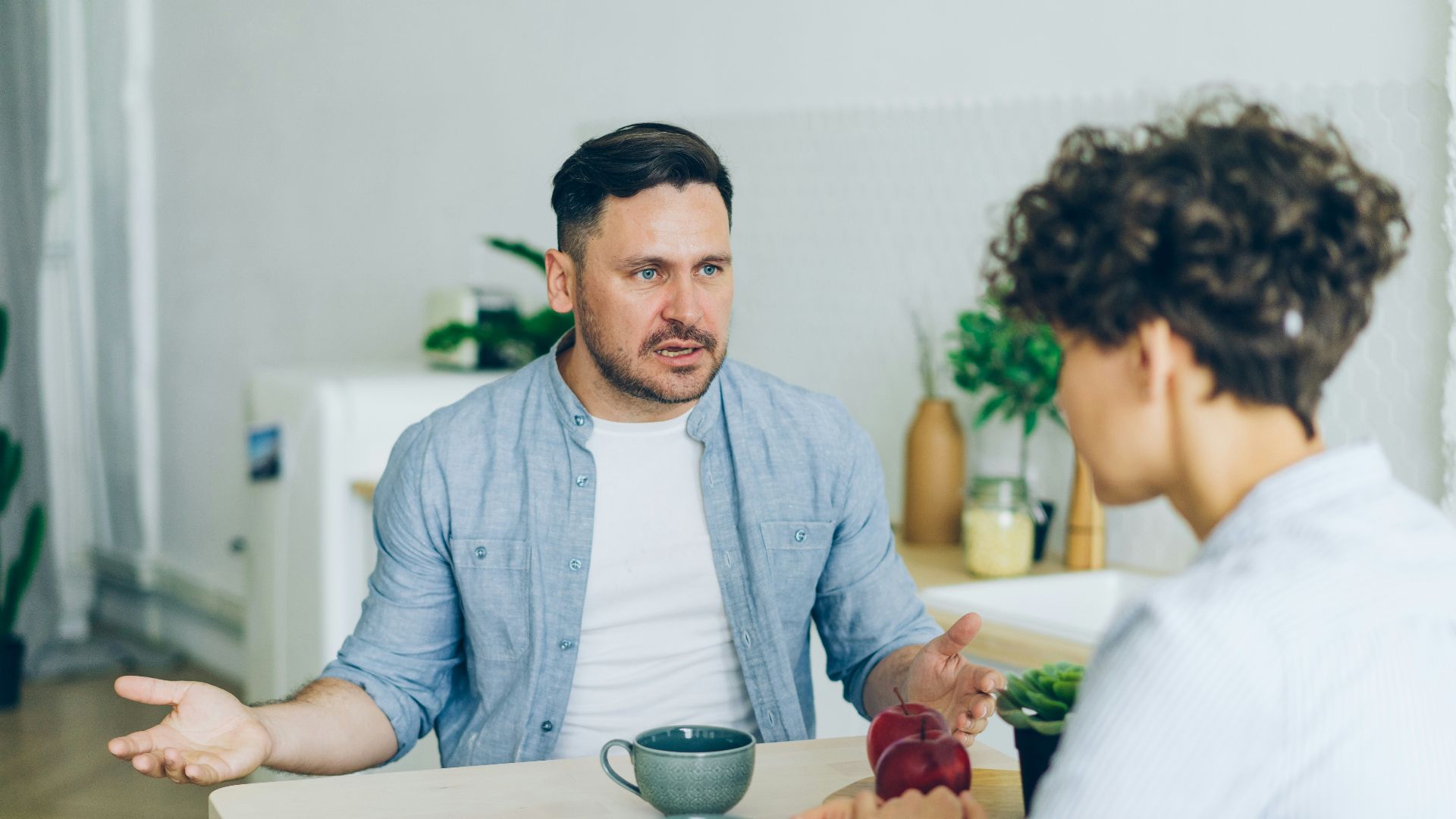 a man sitting at a table talking to a woman