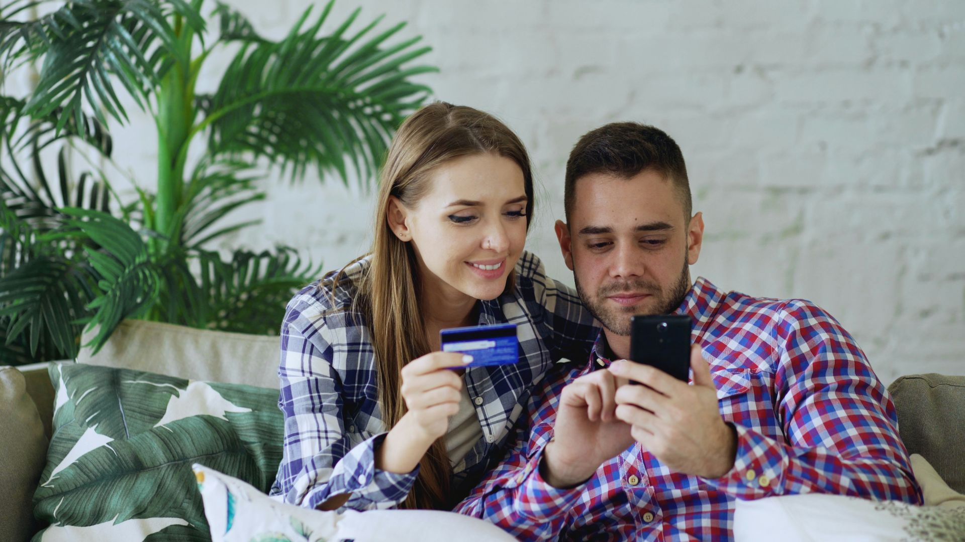 Couple happily shopping online with credit card and phone