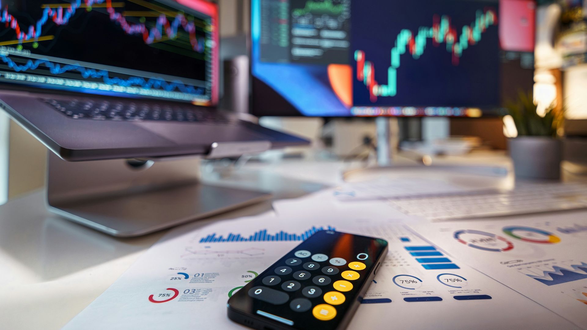 smartphone calculator on desk with financial charts behind