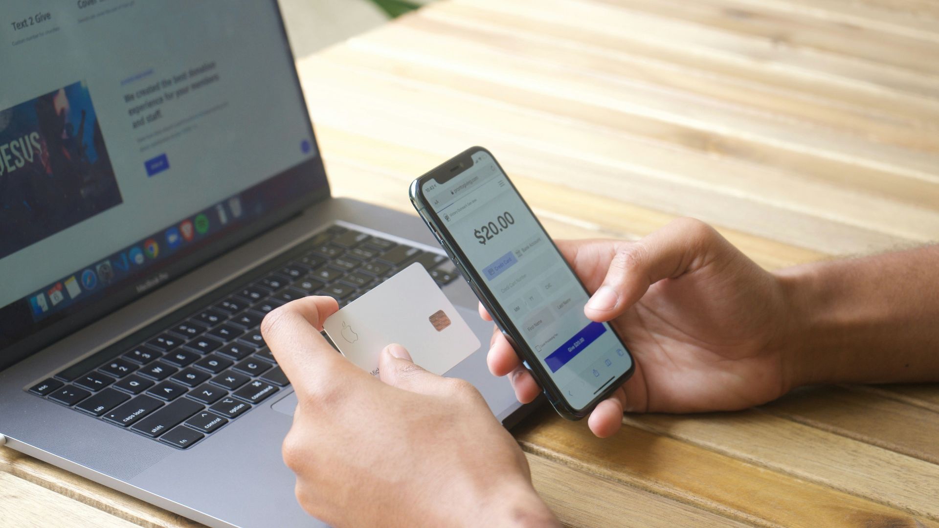 Person using smartphone and credit card with laptop