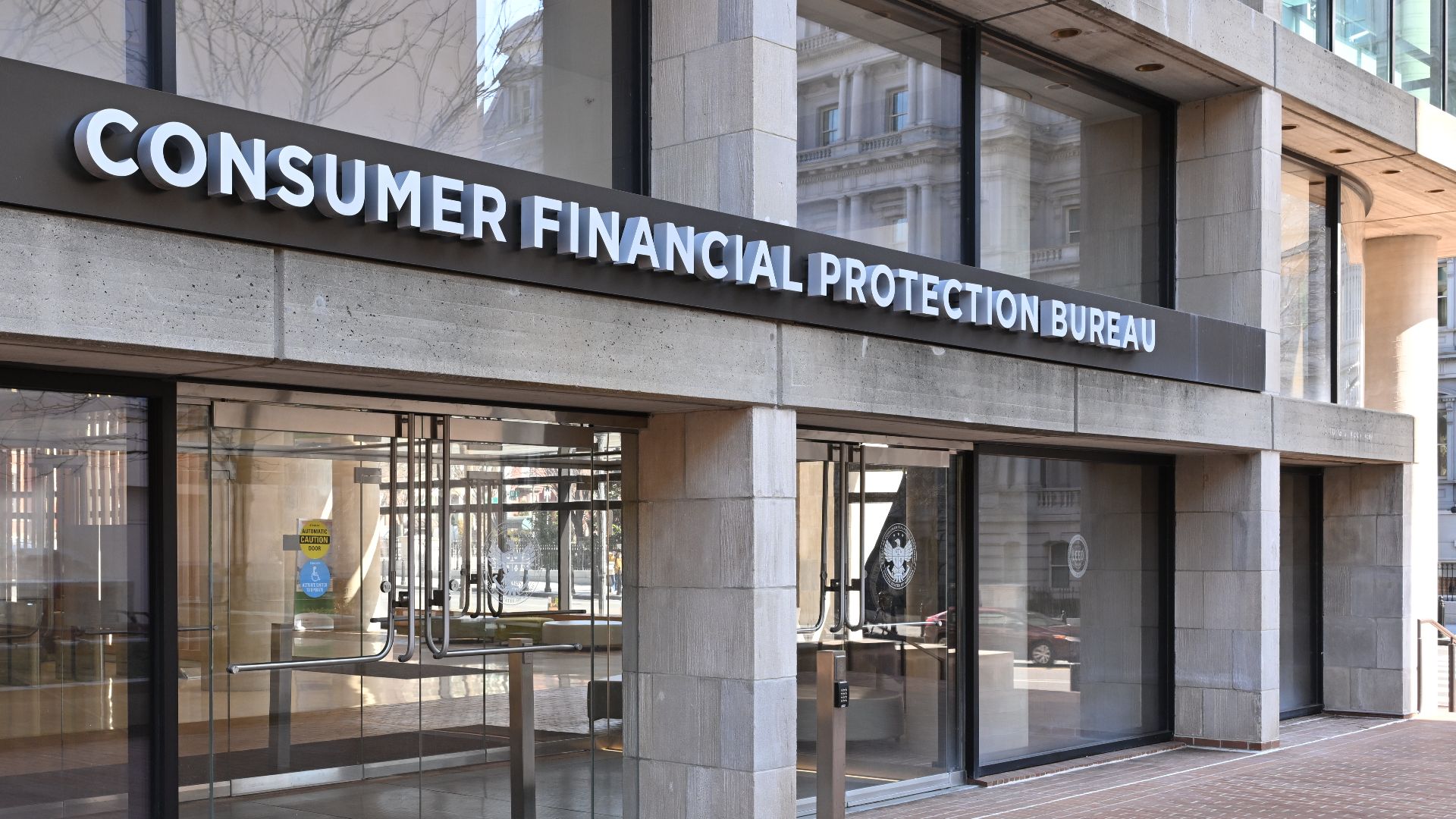 The entrance to the Consumer Financial Protection Bureau headquarters with the bureau's name above it. 1700 G Street NW, Washington, DC 20552.