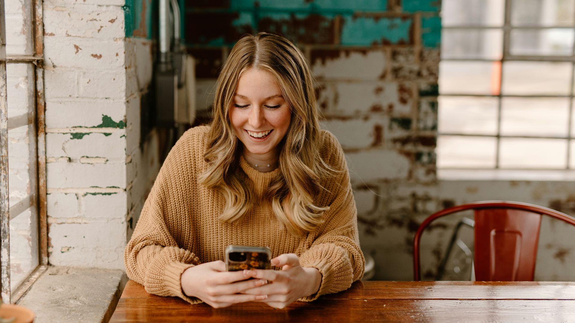 a woman sitting at a table looking at her cell phone