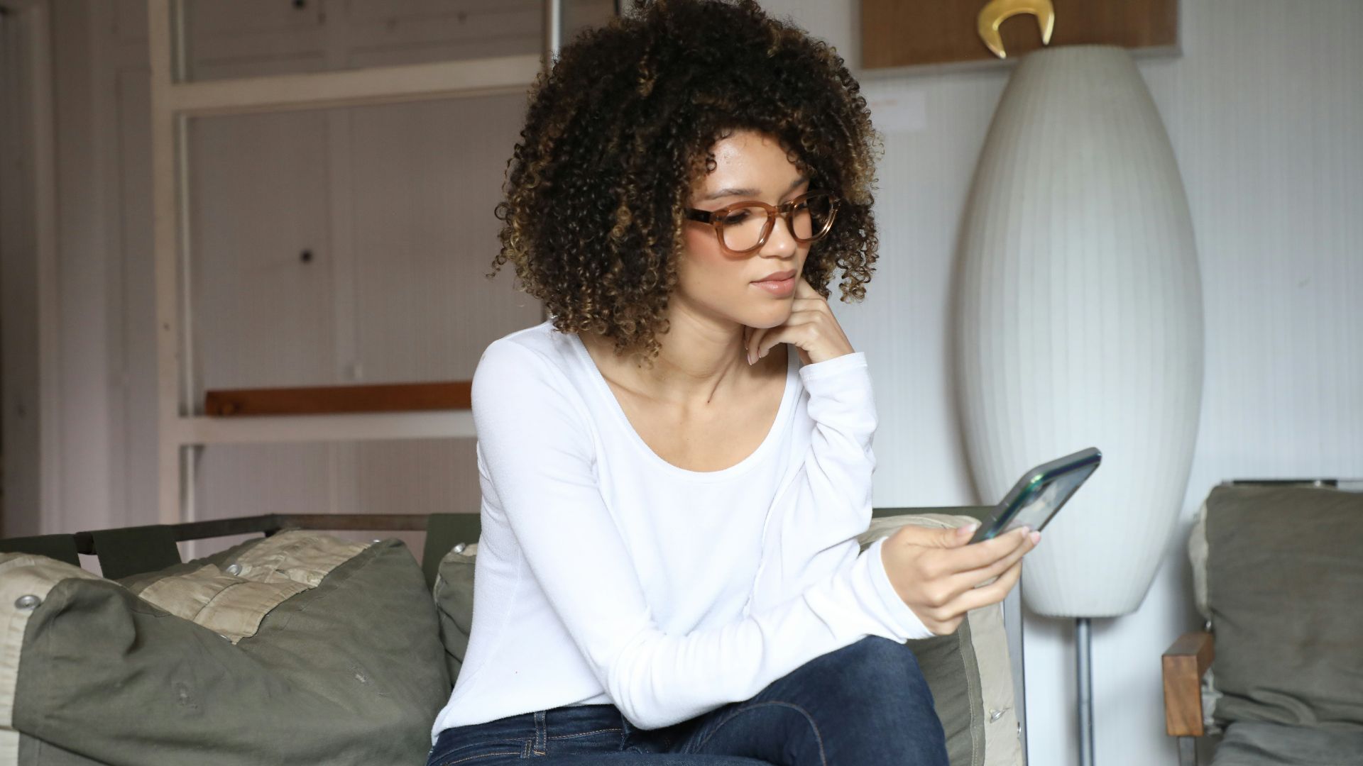 woman in white long sleeve shirt and blue denim jeans sitting on bed