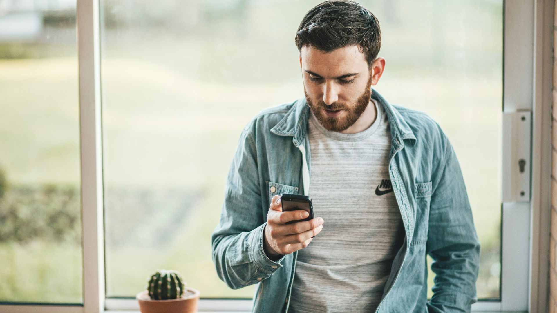 man holding a smartphone near the window