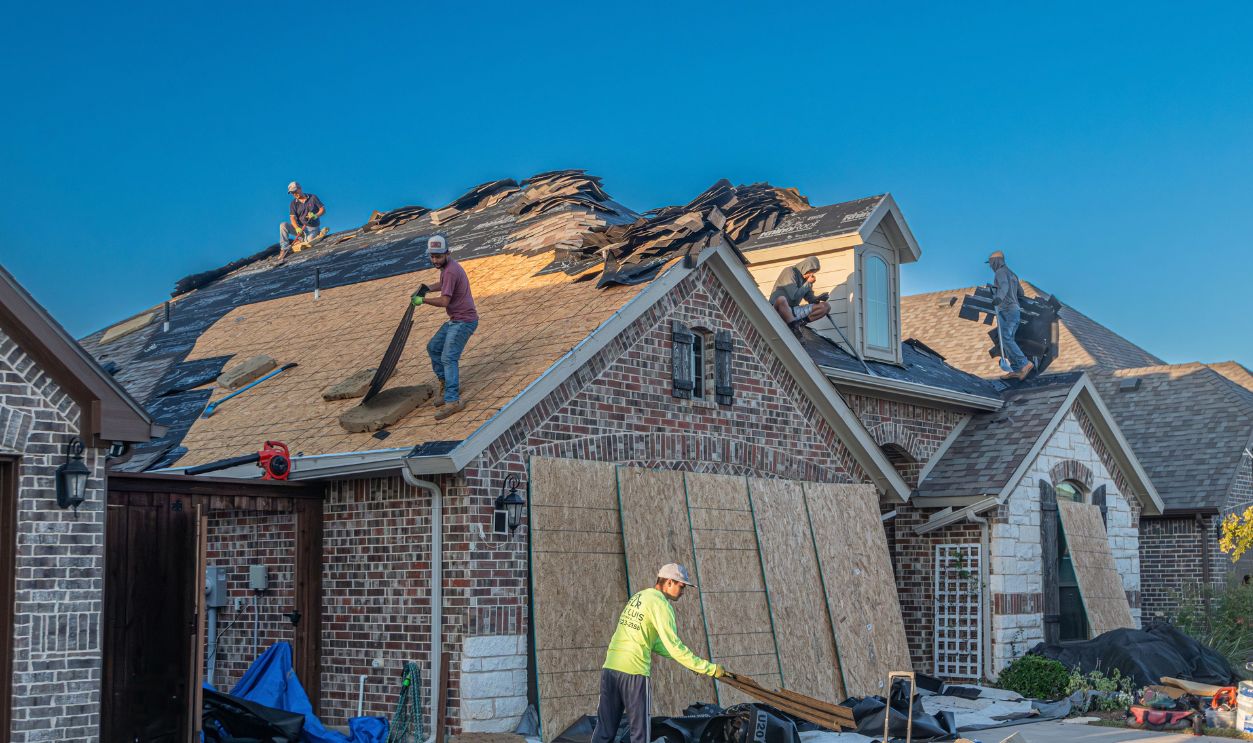 Workers engage in roof replacement on a brick house
