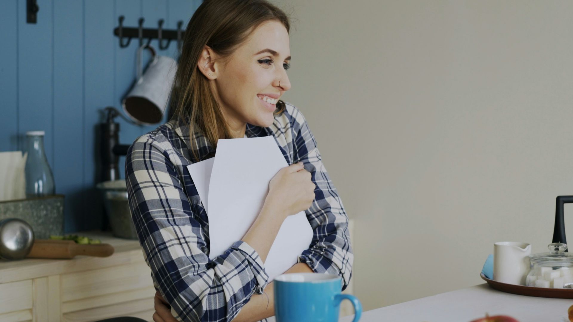 Woman holding book at kitchen table with snacks.