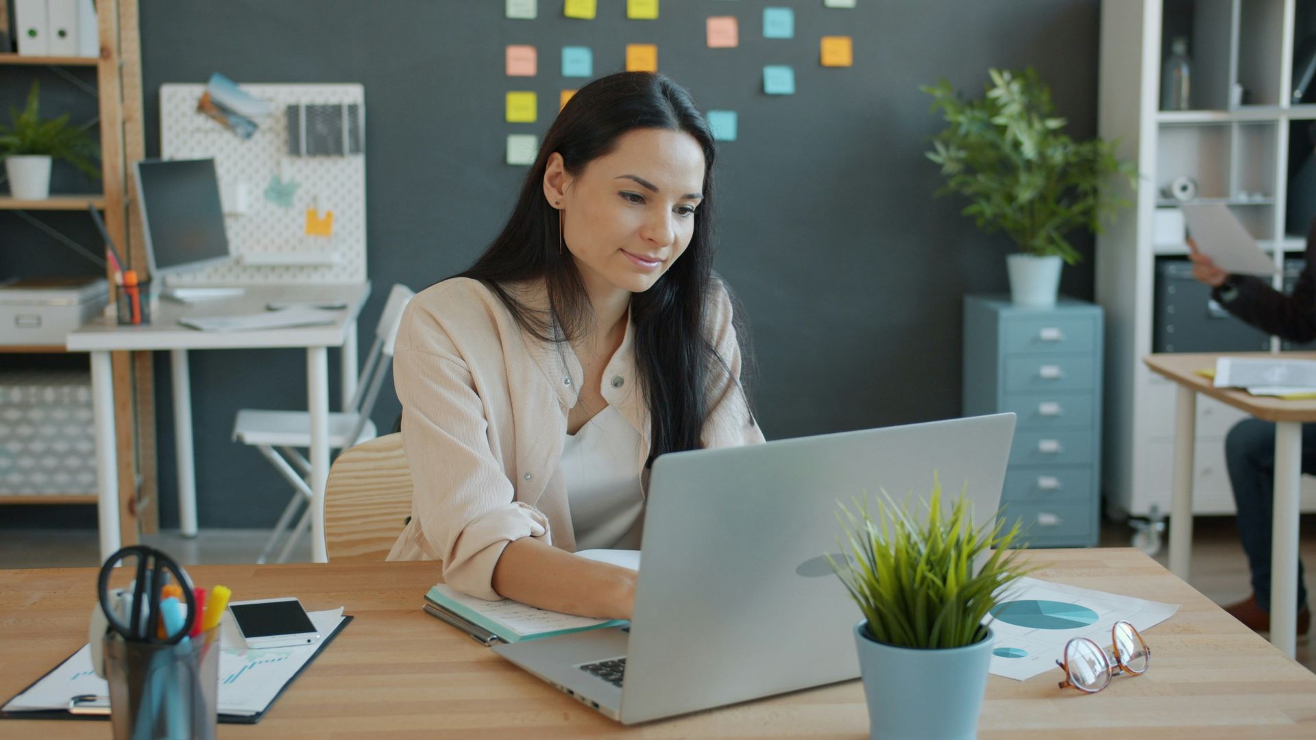 Woman working on a laptop at an office desk.
