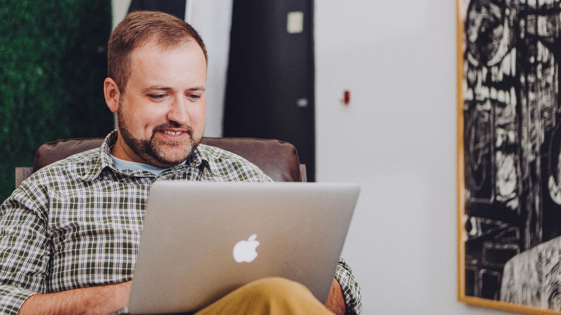 man smiling and using MacBook