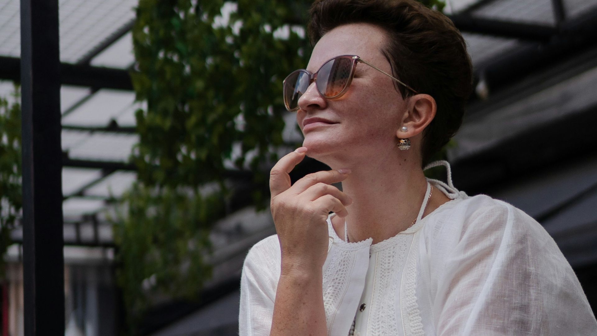 Woman in white shirt wearing sunglasses outdoors