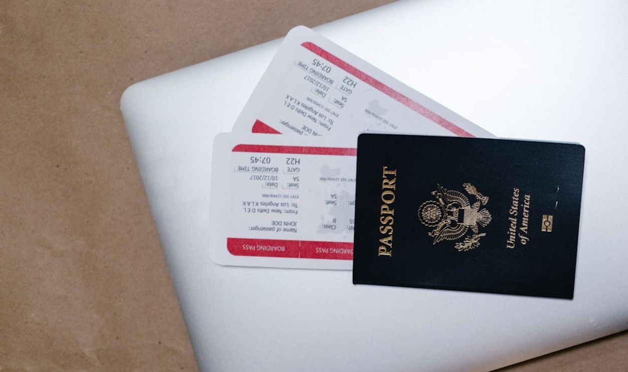 Close-Up Shot of a Passport and Tickets on Top of a Laptop