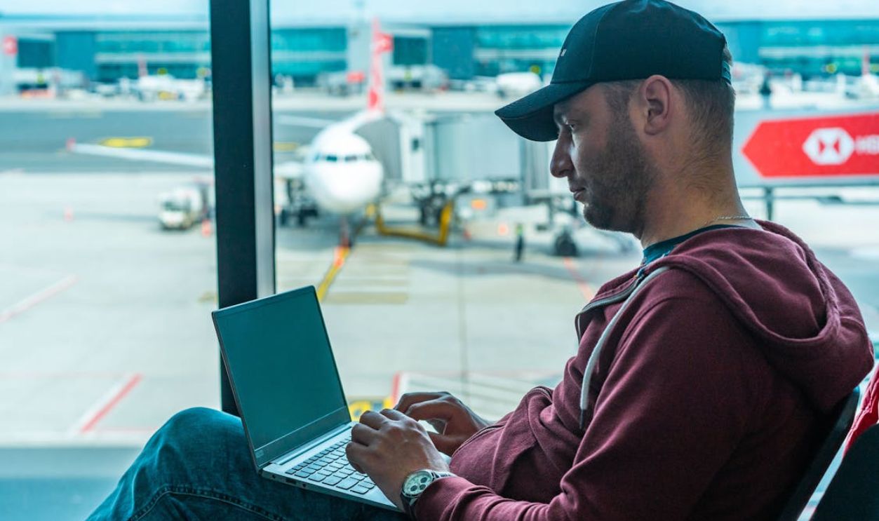Man in Hoodie Jacket Sitting on a Chair Using Laptop