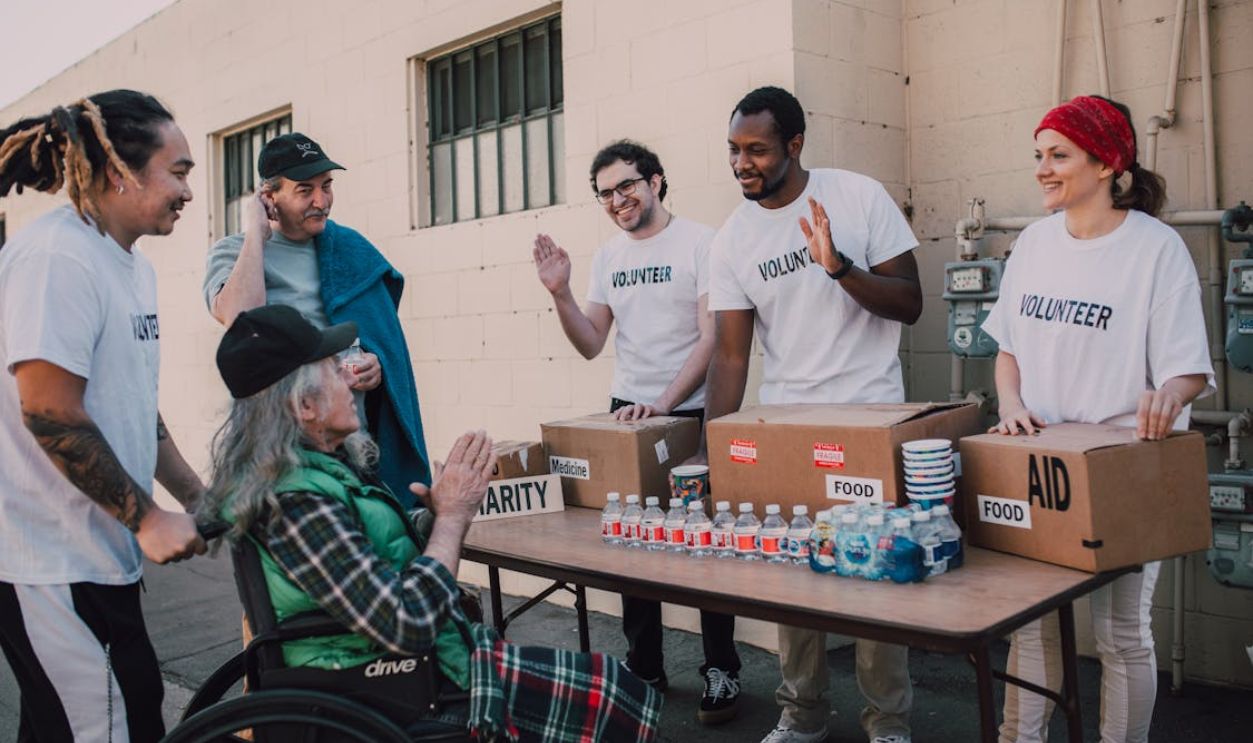 Volunteers Happily Assisting an Old Man on a Wheelchair For Charity