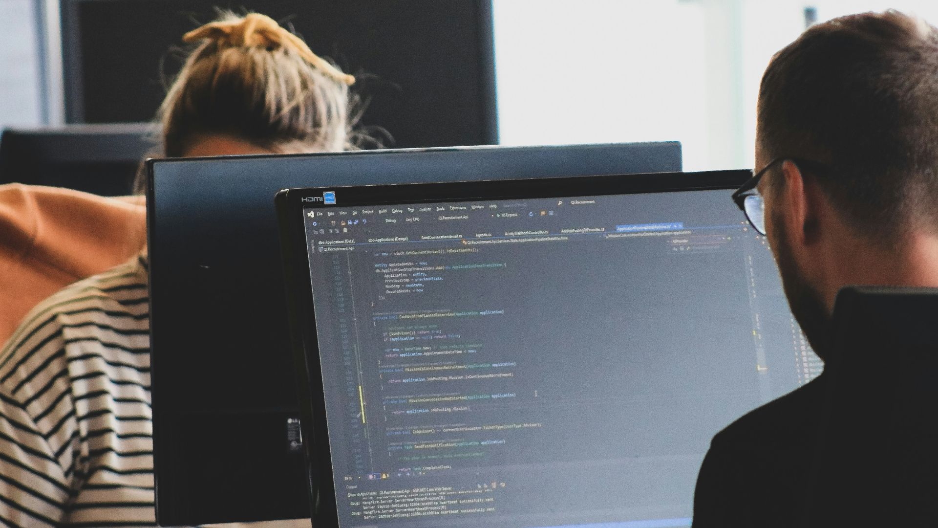 woman in black shirt sitting beside black flat screen computer monitor
