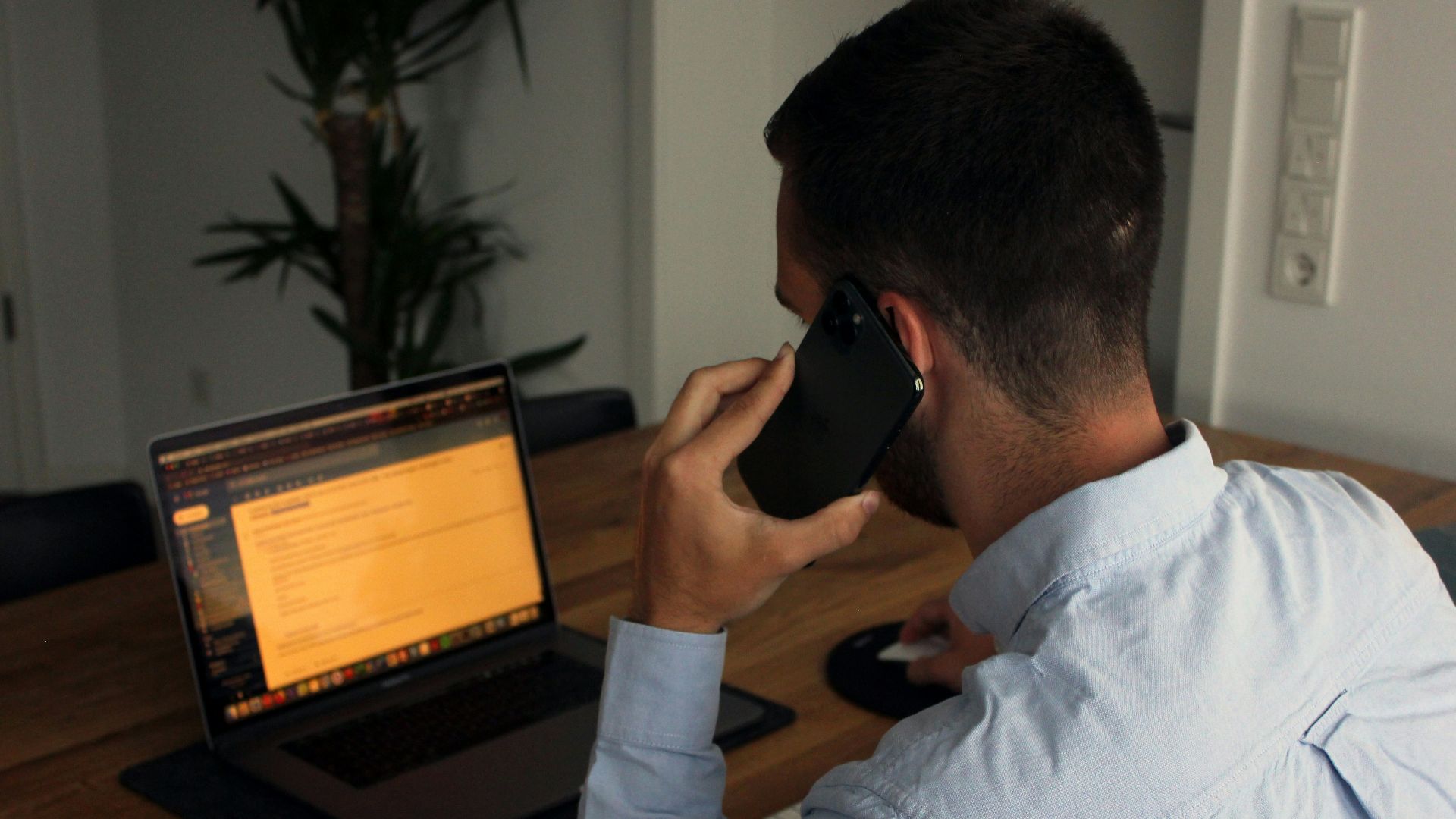 man in blue dress shirt holding black smartphone