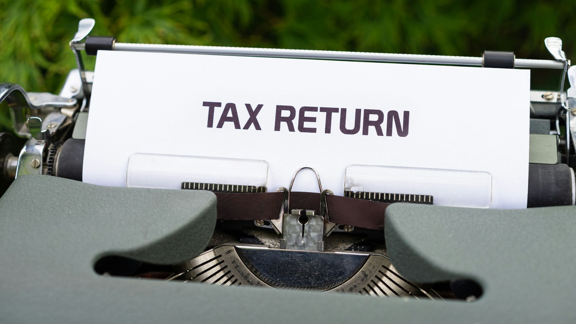 a close up of a typewriter with a tax return sign on it