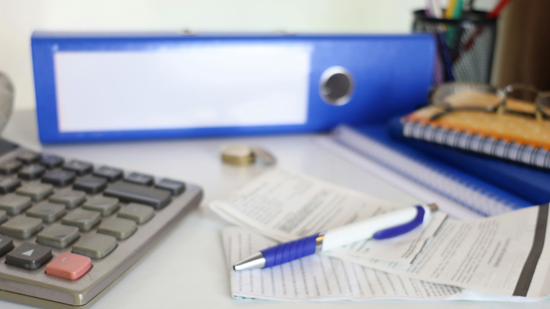 Desk with calculator, papers, and prayer beads.