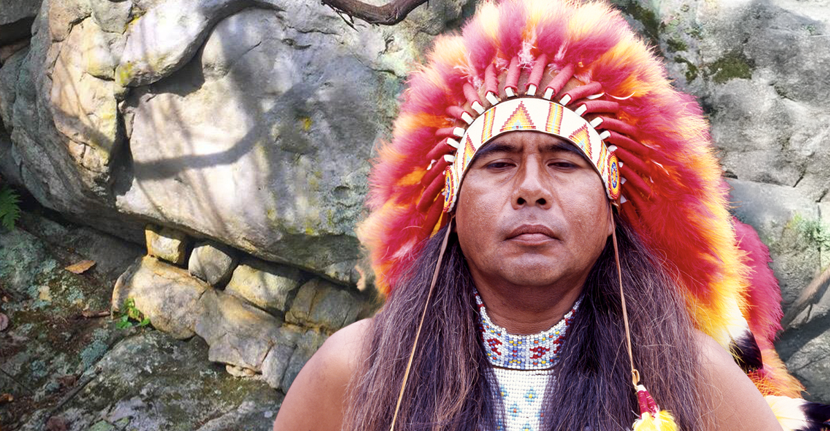 Cherokee man in front of a carved skull rocks