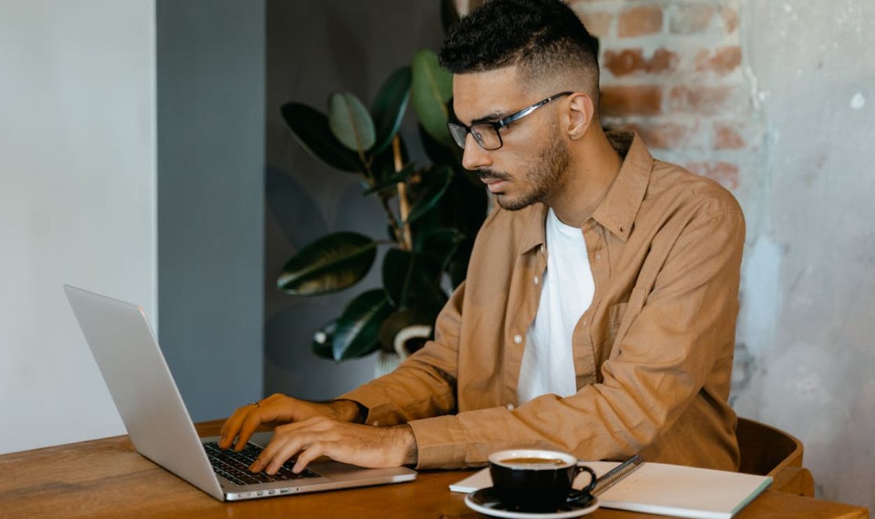 Man in Brown Dress Shirt Typing on a MacBook Pro