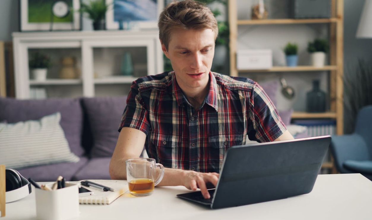 Man in Shirt Working on Laptop at Home