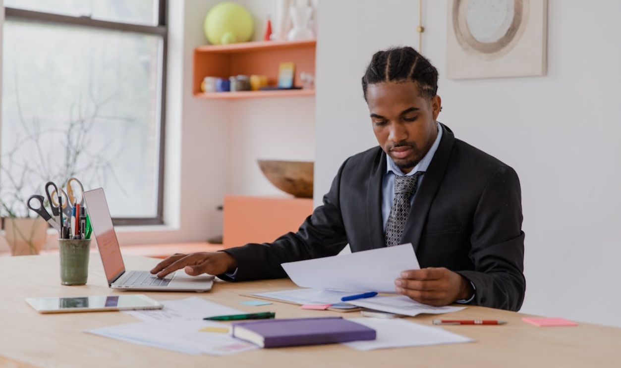 Man Working with Papers Using Laptop