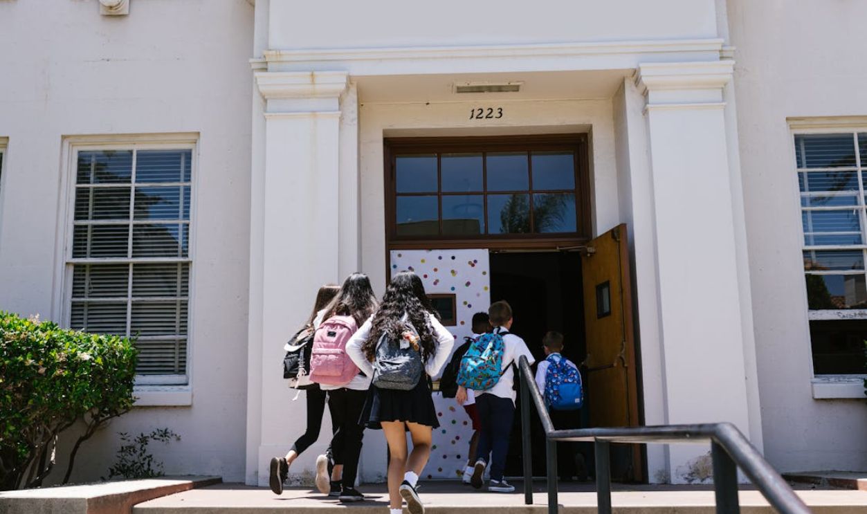 Back View Shot of Students Going Inside the School