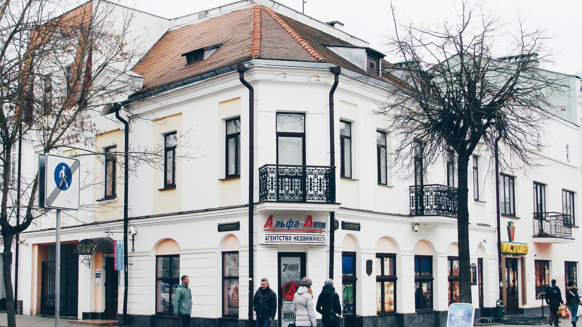 Corner building with people walking on sidewalk.
